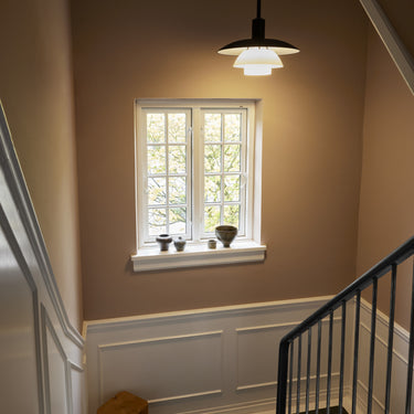 Stairwell with a window, light fixture, and small table.