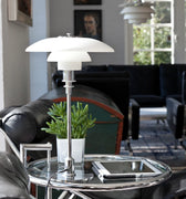 Modern table lamp on a glass table with a blurred living room background