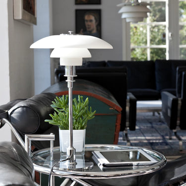 Modern table lamp on a glass table with a blurred living room background