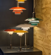 Colorful pendant and table lamps on a dark surface with a stone wall background