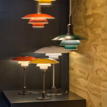 Colorful pendant and table lamps on a dark surface with a stone wall background