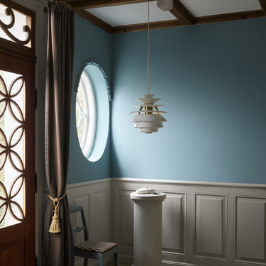 Decorative interior with a round window, hanging light fixture, and wooden chair.