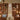 A styled interior showroom featuring multiple mid-century modern lamps and light fixtures displayed on dark wood slat walls above matching wooden sideboards, with a central metallic pedestal holding a small table lamp.