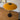 Round mustard yellow table lamp with black base on a wooden floor.