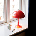 Red table lamp on a windowsill with natural light