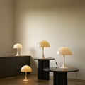 Panthella sizes of table lamps on black tables against a neutral wall.