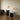 Two table lamps on black round tables against a plain wall.