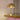Gold or brass 70s table lamp on a wooden surface with a pink curtain in the background