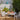 Outdoor patio setting with a table set for a meal, surrounded by greenery.