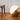 Gold and white round floor lamp on a wooden floor with a wooden stool against a white paneled wall.
