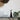 Decorative items on a marble surface with a plant in the corner