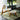 Modern chair and ottoman on a green rug with a view of a garden.