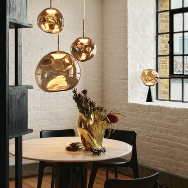 Dining area with gold pendant lights, round table, and black chairs.