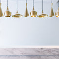 Gold pendant lights hanging above a marble countertop with black stools.