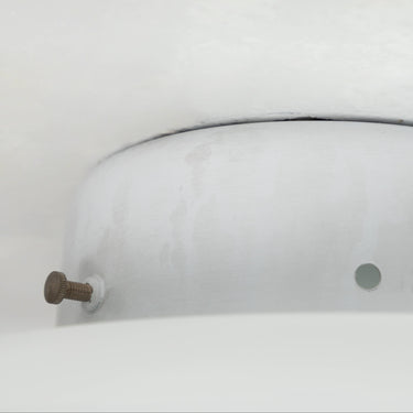Round metallic object with a central screw on a white background