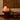 Lamp on a wooden table with decorative wall art and plant in the background