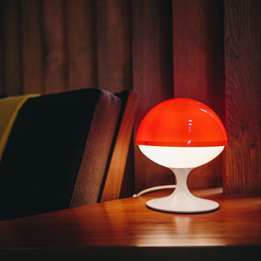 max bill red and white mushroom lamp on wood table with sofa in background