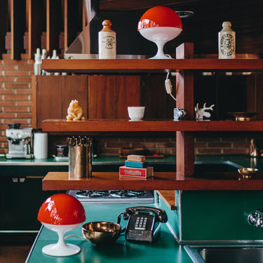 Vintage kitchen with wooden shelves, red and white lamps, and a green countertop.