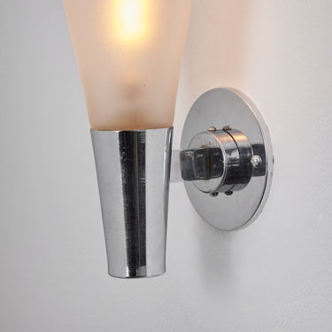 Wall-mounted light fixture with a chrome finish and glass shade on a white background for Two Enlighten