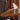 Small white lamp on a wooden surface next to a dark upholstered chair