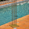 Metal bertoai sculpture with vertical rods on a tiled poolside area