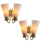 Two gold wall sconces with white lampshades on a white background