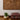 Wooden wall art with concentric circle design on a white wall, with a plant and cushion in the foreground.