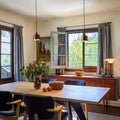 Dining room with wooden table, chairs, and large windows.