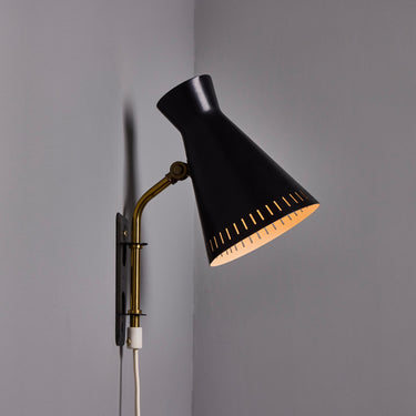side view Black wall-mounted midcentury diabolo shaped lamp with plug and brass arm by Mauri Almari on a white background