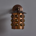 copper wall sconce with spherical design on a gray background