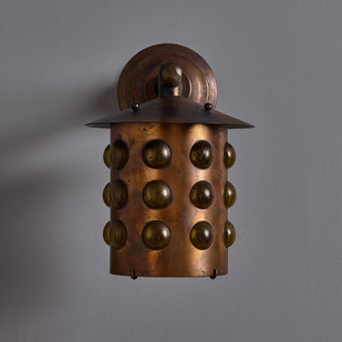 copper wall sconce with spherical design on a gray background