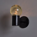 Black wall-mounted light fixture with a textured glass shade on a gray background