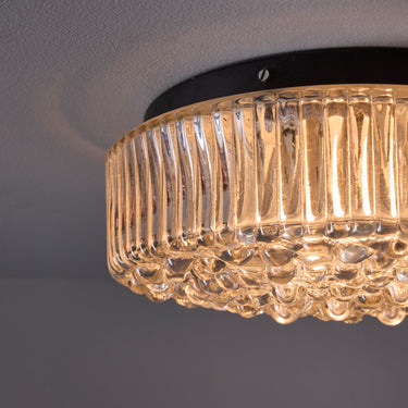 Ceiling light fixture with ribbed glass shade on a gray background