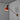 Wall-mounted lamp with red shade and gold arm against a gray wall