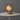 Table lamp with a gold base and beige shade on a white table against a gray background
