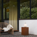 Modern outdoor patio with wicker chair, hanging light, portable glass light and side table.