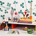Desk with decorative wood dolls by Alexander Girard against a wallpapered wall