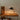 Wooden shelf with a lamp and books against a white wall