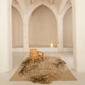Wooden chair on a textured rug in a room with high arched ceilings and white walls.