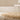 Beige  deep shag rug on a light wooden floor with a white chair against a beige wall.