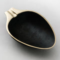 Black ceramic dish with gold rim on a light gray background