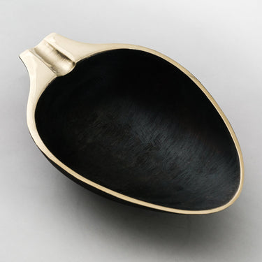 Black ceramic dish with gold rim on a light gray background