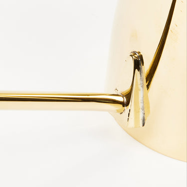Close-up of a brass watering can frame on a white background