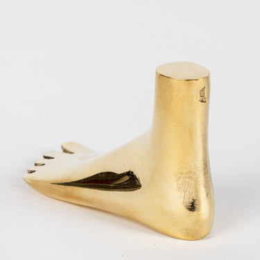 Polished brass stamped aubock foot paperweight object on a white background
