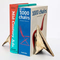 brass geometric bookend on a stack of books with visible titles.