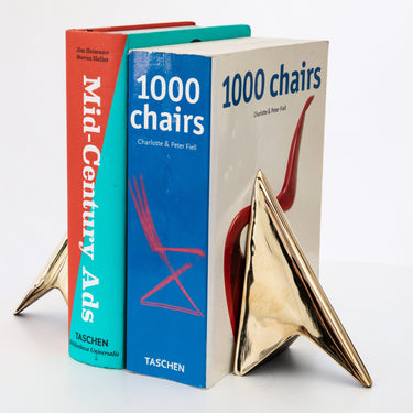 brass geometric bookend on a stack of books with visible titles.