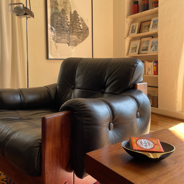 Brown leather armchair in a living room with a wooden table and decorative items.