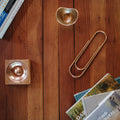 Decorative items including a gold paper clip, small bowl, and books on a wooden surface.