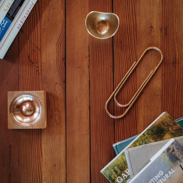 Decorative items including a gold paper clip, small bowl, and books on a wooden surface.