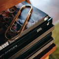 Stack of bookss with a gold paper clip on top, against a blurred background.